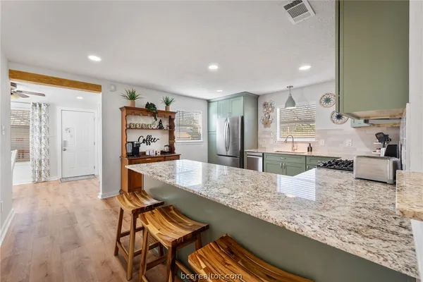 a large kitchen with kitchen island a large counter top sink and stainless steel appliances