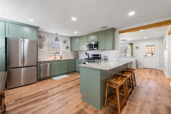 a kitchen with stainless steel appliances granite countertop a refrigerator a sink a stove and a wooden floors