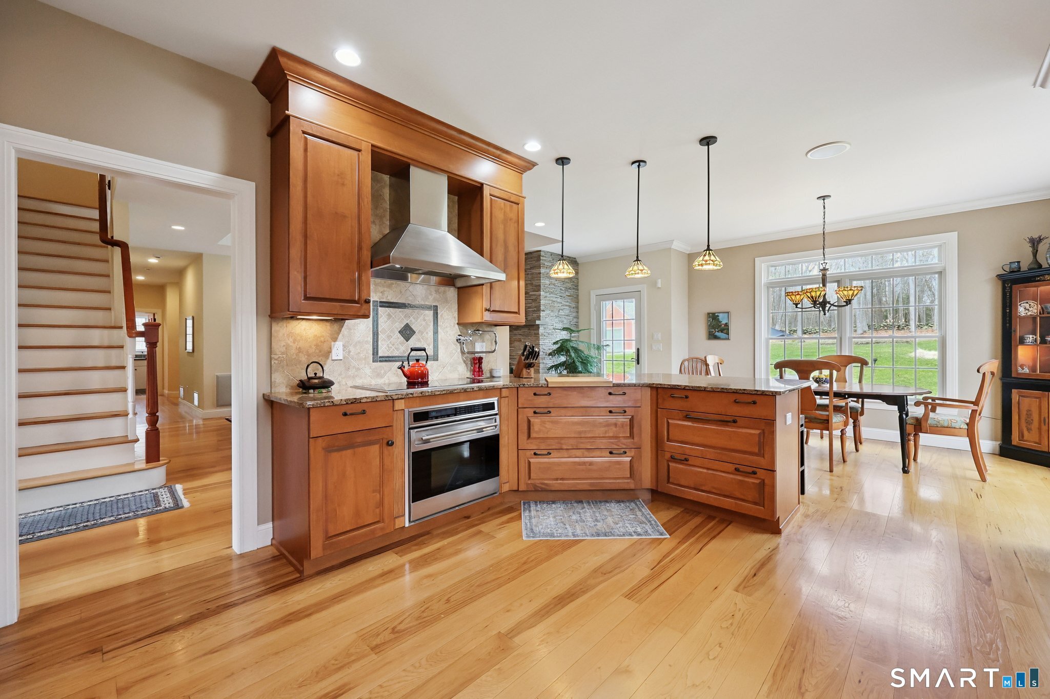 15 Mains Way Preston, CT 06365 - Photo 5 of 40 a kitchen with stainless steel appliances kitchen island granite countertop a stove top oven a sink dishwasher a dining table and chairs with wooden floor