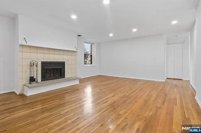 a view of empty room with wooden floor and fireplace
