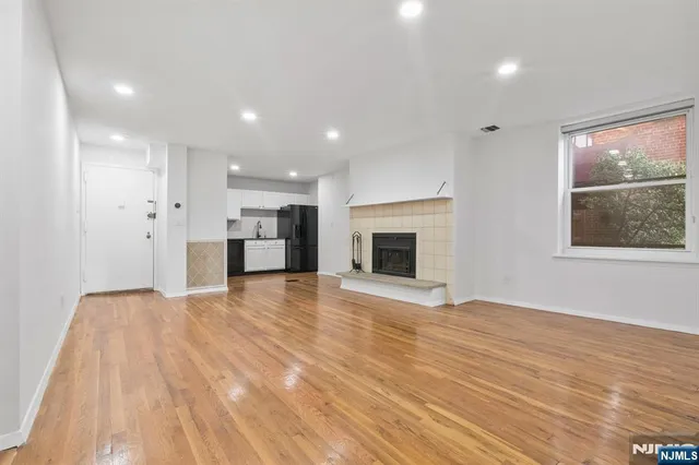 a view of empty room with wooden floor and fireplace