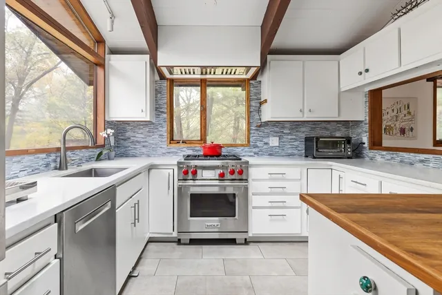 a kitchen with stainless steel appliances granite countertop a sink window and cabinets