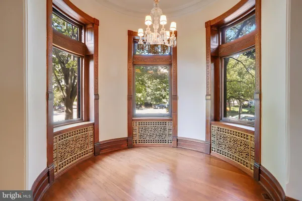a view of an empty room with wooden floor fireplace and a window