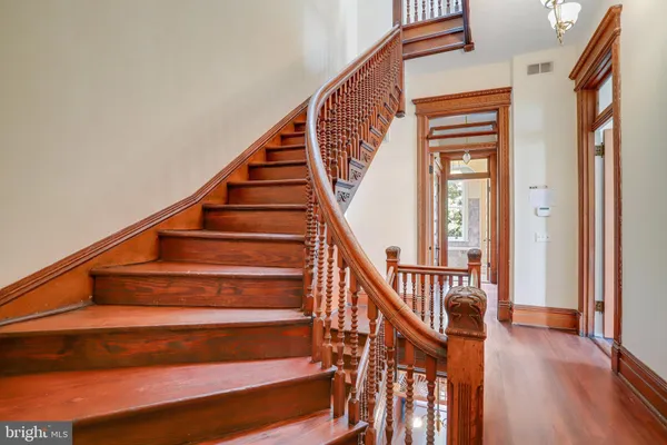 a view of a hallway with wooden floor and staircase