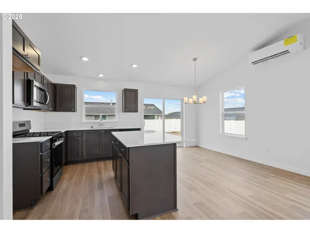 a kitchen with stainless steel appliances granite countertop a refrigerator a sink dishwasher a stove and a oven with wooden floor