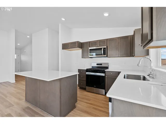 a kitchen with stainless steel appliances kitchen island granite countertop a sink a stove and a refrigerator