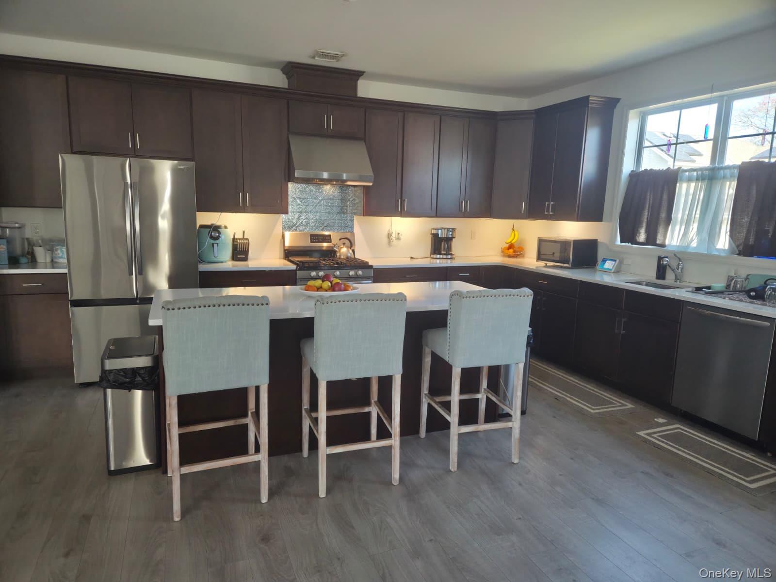 9 Lilac Lane Ridge, NY 11961 - Photo 5 of 9 a kitchen with stainless steel appliances a table chairs refrigerator a sink and dishwasher