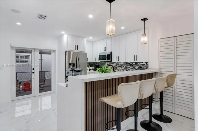 a view of kitchen with stainless steel appliances granite countertop a table chairs and a refrigerator