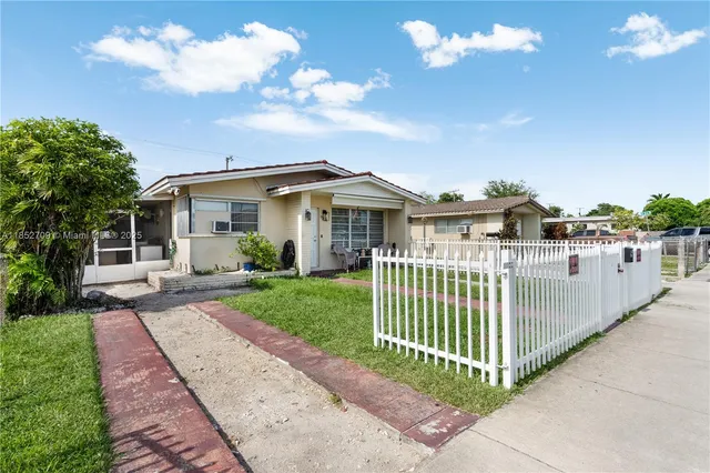 a view of a white house in the middle of a garden