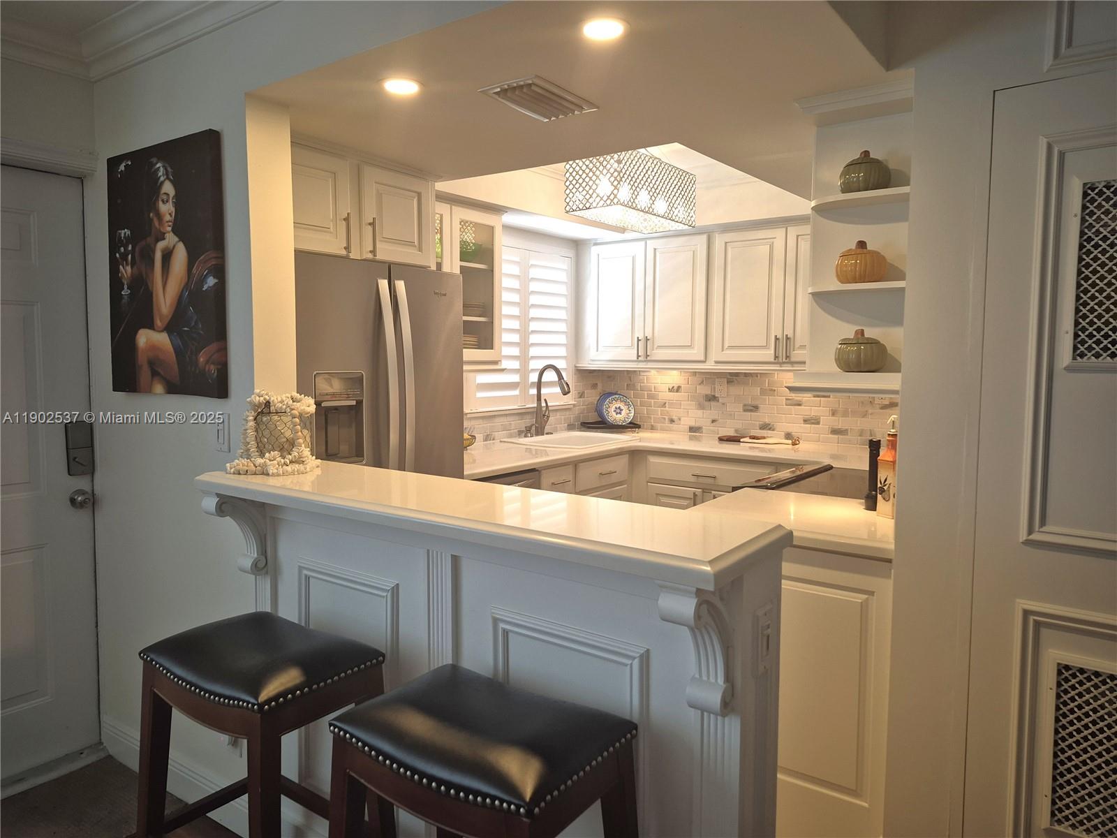 535 Hendricks Isle, Unit 306 Fort Lauderdale, FL 33301 - Photo 8 of 32 a kitchen with kitchen island granite countertop a sink cabinets and a refrigerator
