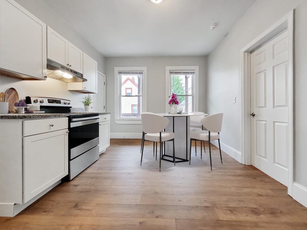 108 Callender Street, Unit 2 Boston, MA 02124 - Photo 2 of 11 a kitchen with granite countertop a table chairs stove and cabinets
