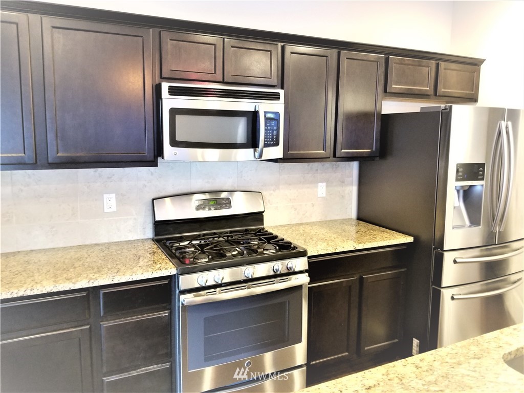 4818 155th Place Southwest, Unit 11 Edmonds, WA 98026 - Photo 10 of 30 a kitchen with stainless steel appliances granite countertop a refrigerator a stove and a sink
