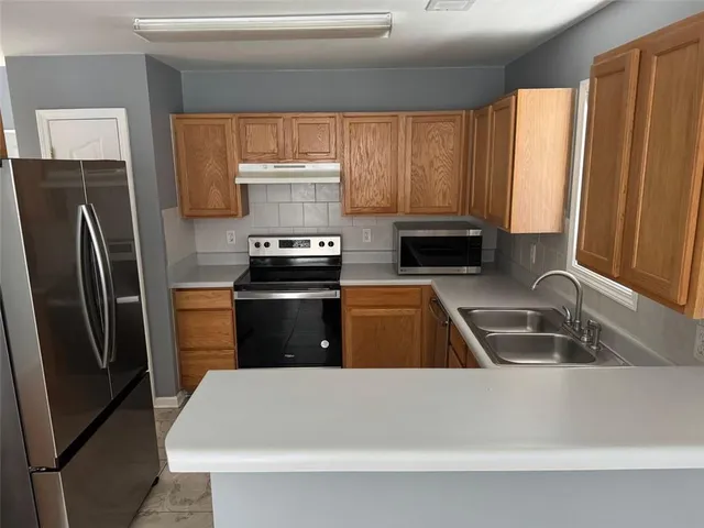 a kitchen with a refrigerator a stove a sink and a window