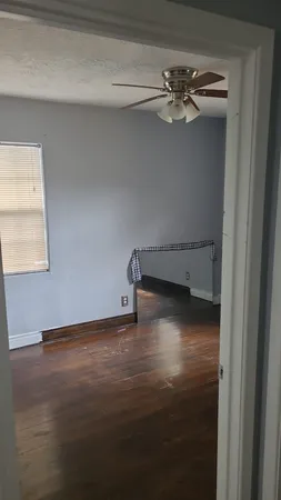 a view of an empty room with wooden floor and a window