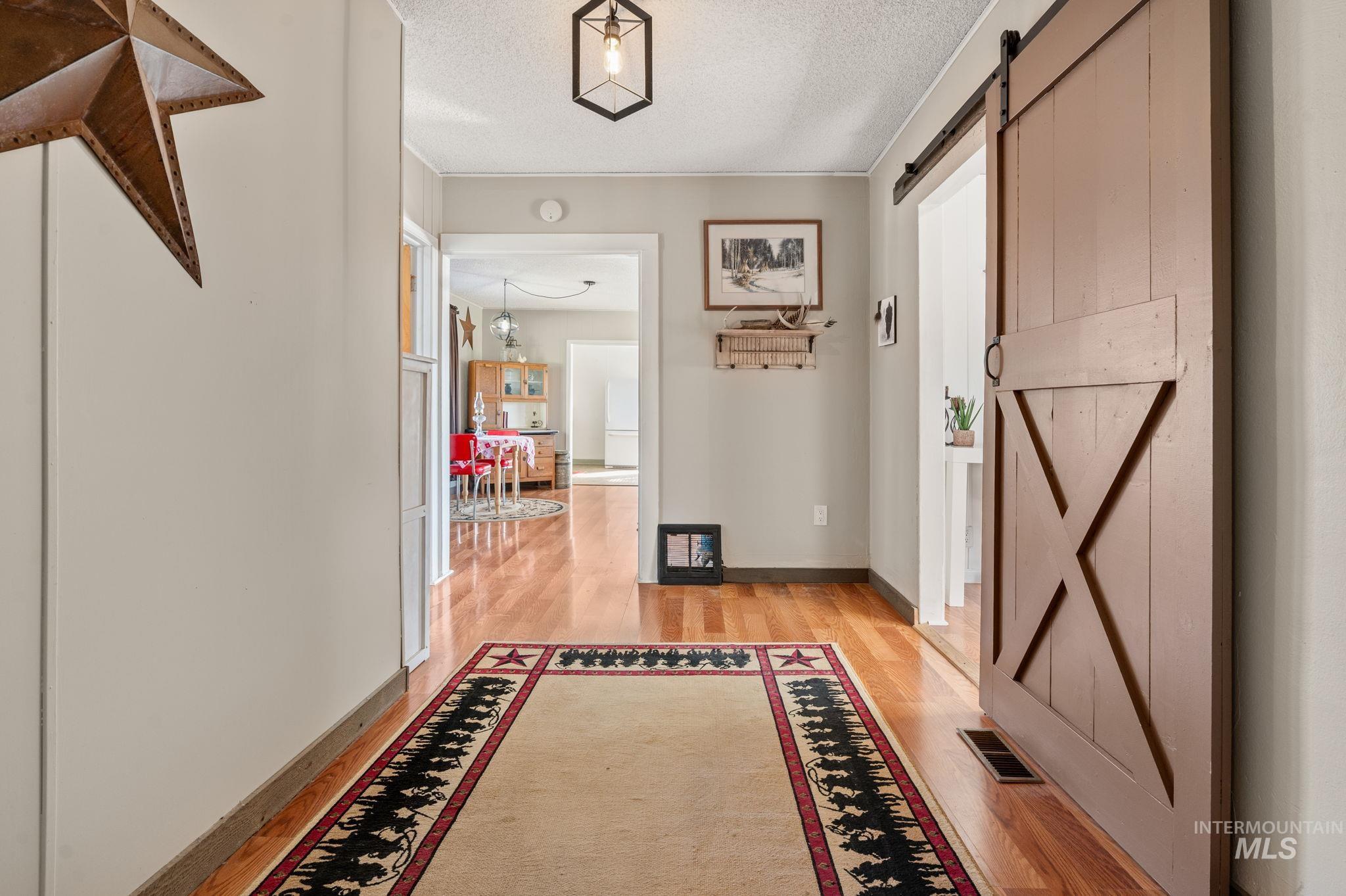 2208 4th Avenue Clarkston, WA 99403 - Photo 15 of 27 Hallway with a barn door, a textured ceiling, and light wood-style flooring