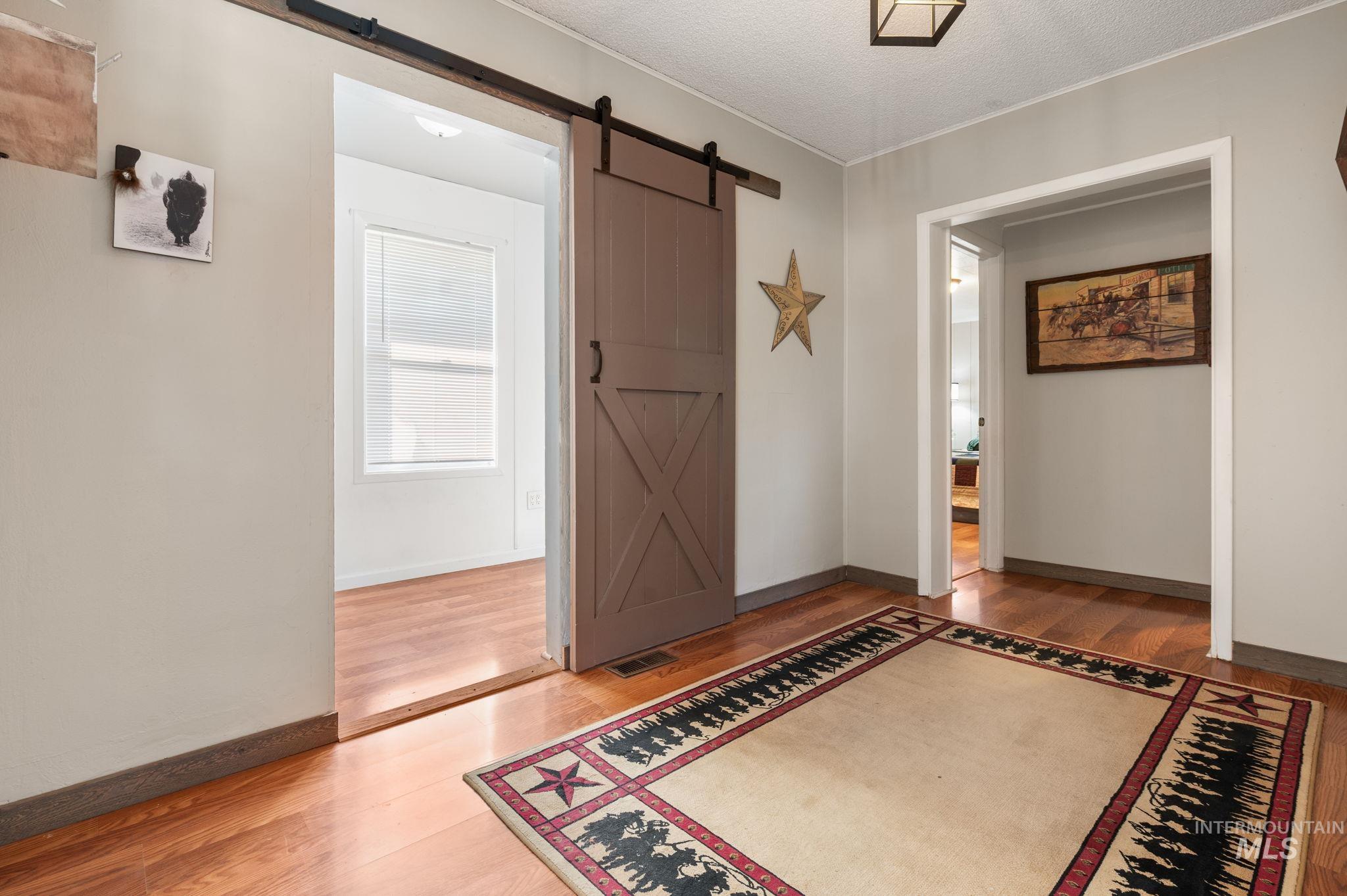 2208 4th Avenue Clarkston, WA 99403 - Photo 16 of 27 Entryway featuring light wood finished floors, a barn door, a textured ceiling, and crown molding