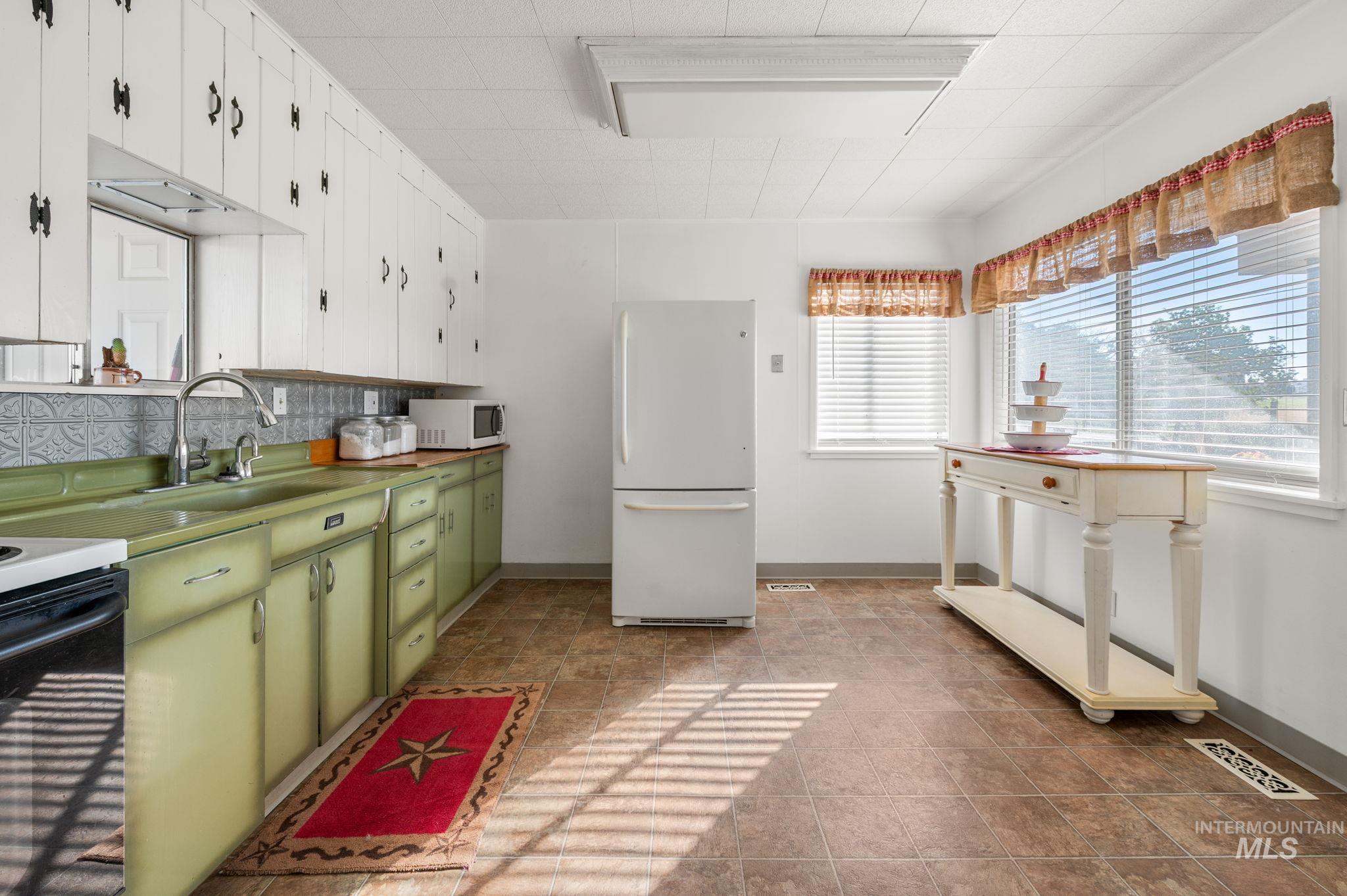 2208 4th Avenue Clarkston, WA 99403 - Photo 5 of 27 Kitchen with green cabinetry, white appliances, white cabinets, and tasteful backsplash