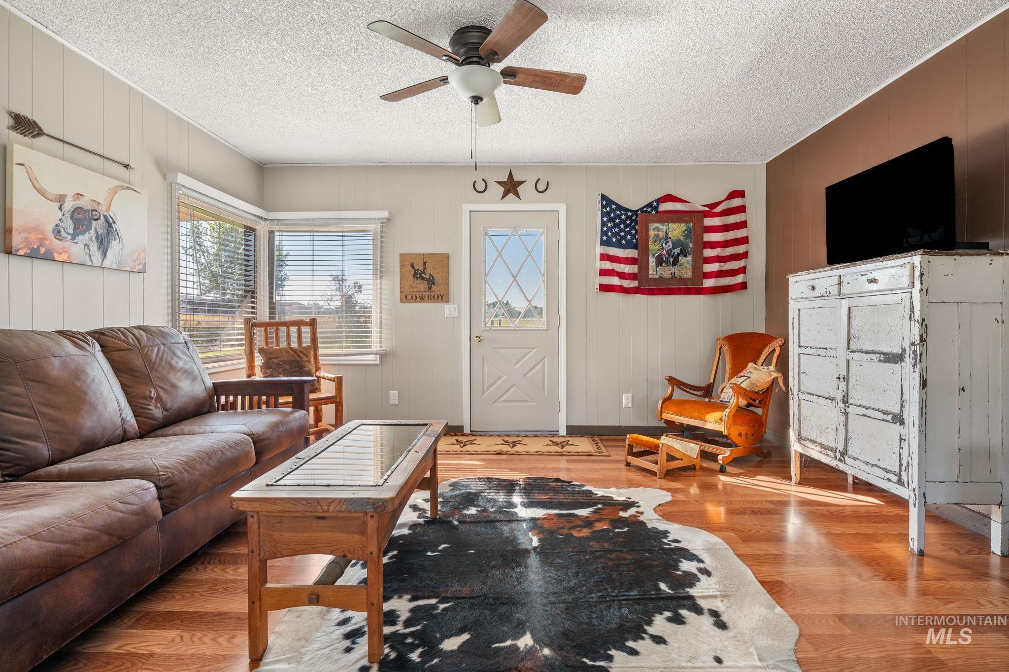 2208 4th Avenue Clarkston, WA 99403 - Photo 9 of 27 Living area featuring light wood finished floors, a textured ceiling, wooden walls, and ceiling fan