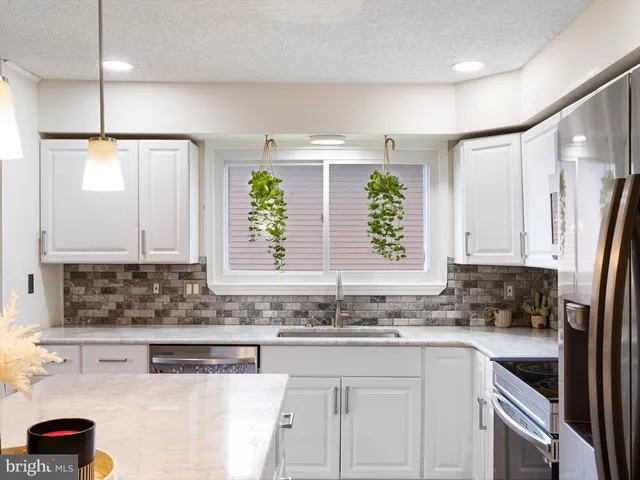 a kitchen with stainless steel appliances granite countertop a sink a refrigerator and a counter space