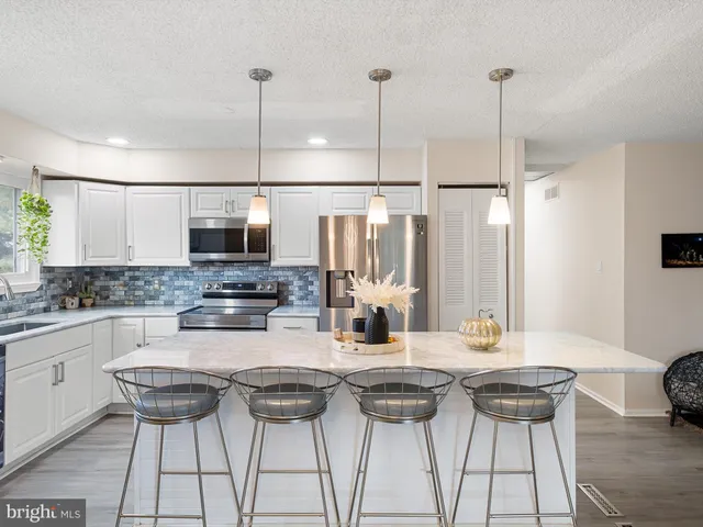 a kitchen with stainless steel appliances kitchen island granite countertop a stove a sink a microwave and a refrigerator