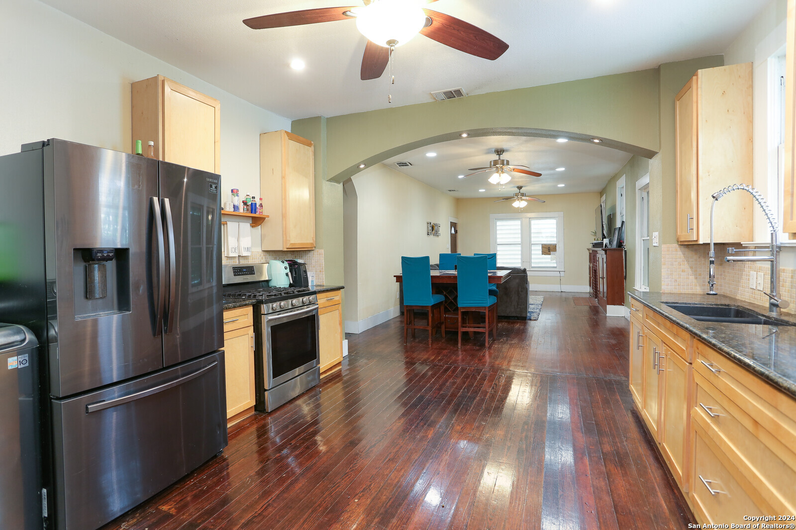 511 Devine Street San Antonio, TX 78210 - Photo 11 of 28 a kitchen with granite countertop a refrigerator a stove top oven a dining table and chairs with wooden floor