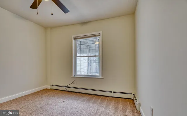 an empty room with ceiling fan and window