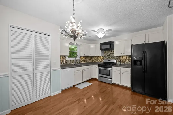 a kitchen with granite countertop white cabinets and stainless steel appliances