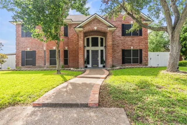 a front view of a house with yard and large tree