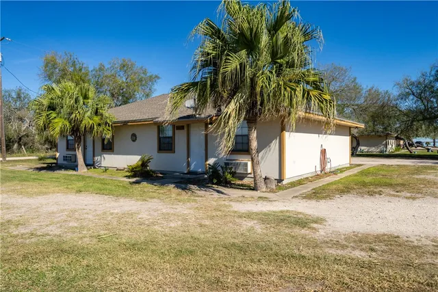 a view of a house with a yard and palm trees