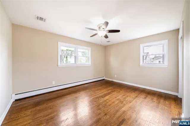 a view of an empty room with a window and wooden floor