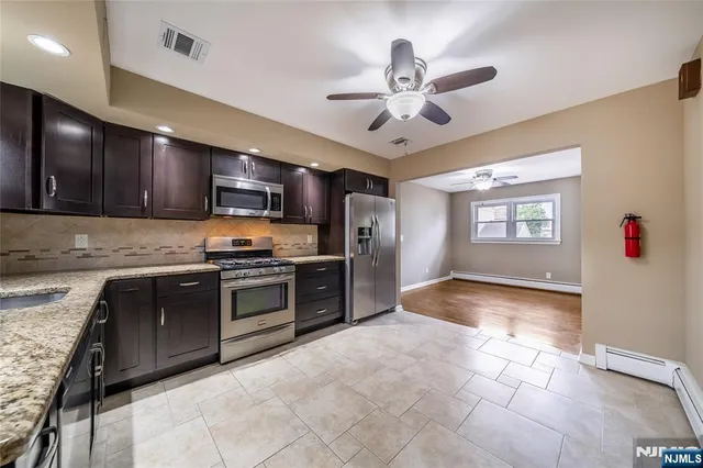 a large kitchen with stainless steel appliances granite countertop a stove sink and cabinets