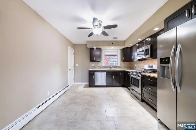 a kitchen with stainless steel appliances granite countertop a refrigerator a oven a sink with dishwasher and white cabinets