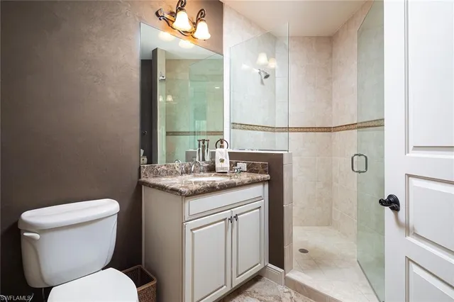 a bathroom with a granite countertop toilet sink and mirror