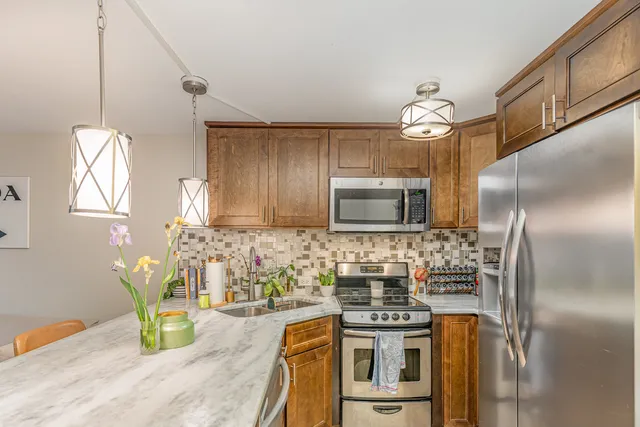 a kitchen with stainless steel appliances granite countertop a sink and a refrigerator