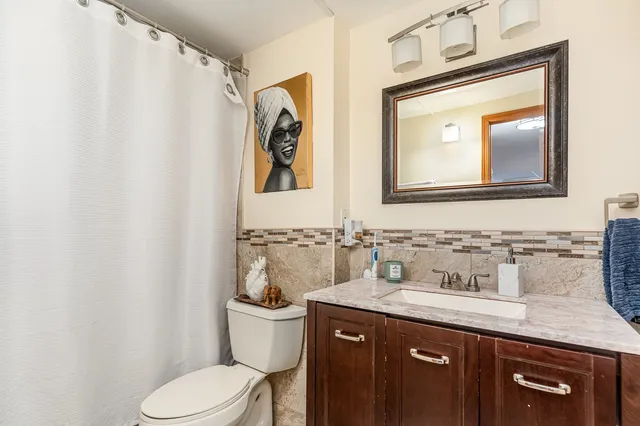 a bathroom with a granite countertop toilet sink and mirror