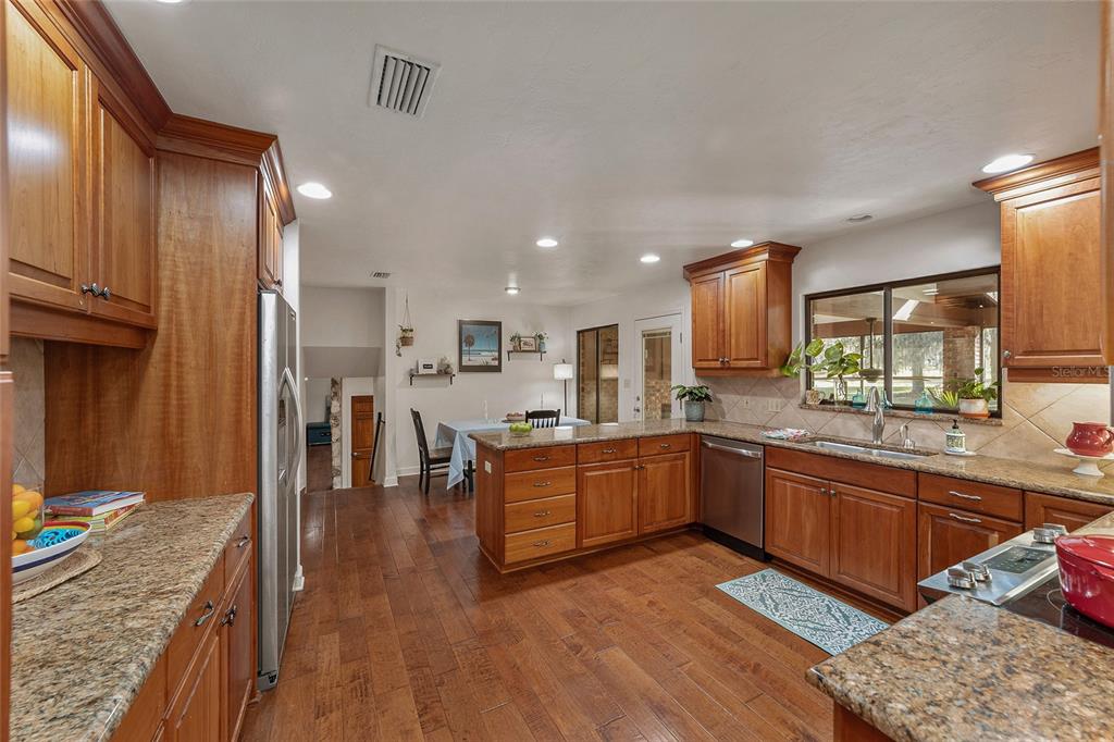 6015 Southwest 36th Way Gainesville, FL 32608 - Photo 23 of 67 a kitchen with stainless steel appliances granite countertop a sink counter space and wooden floor