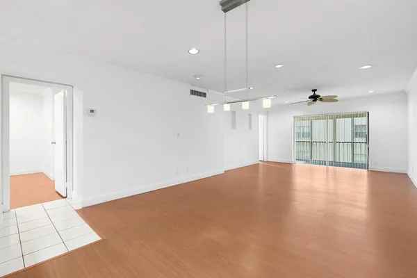 a view of an empty room with chandelier and a kitchen