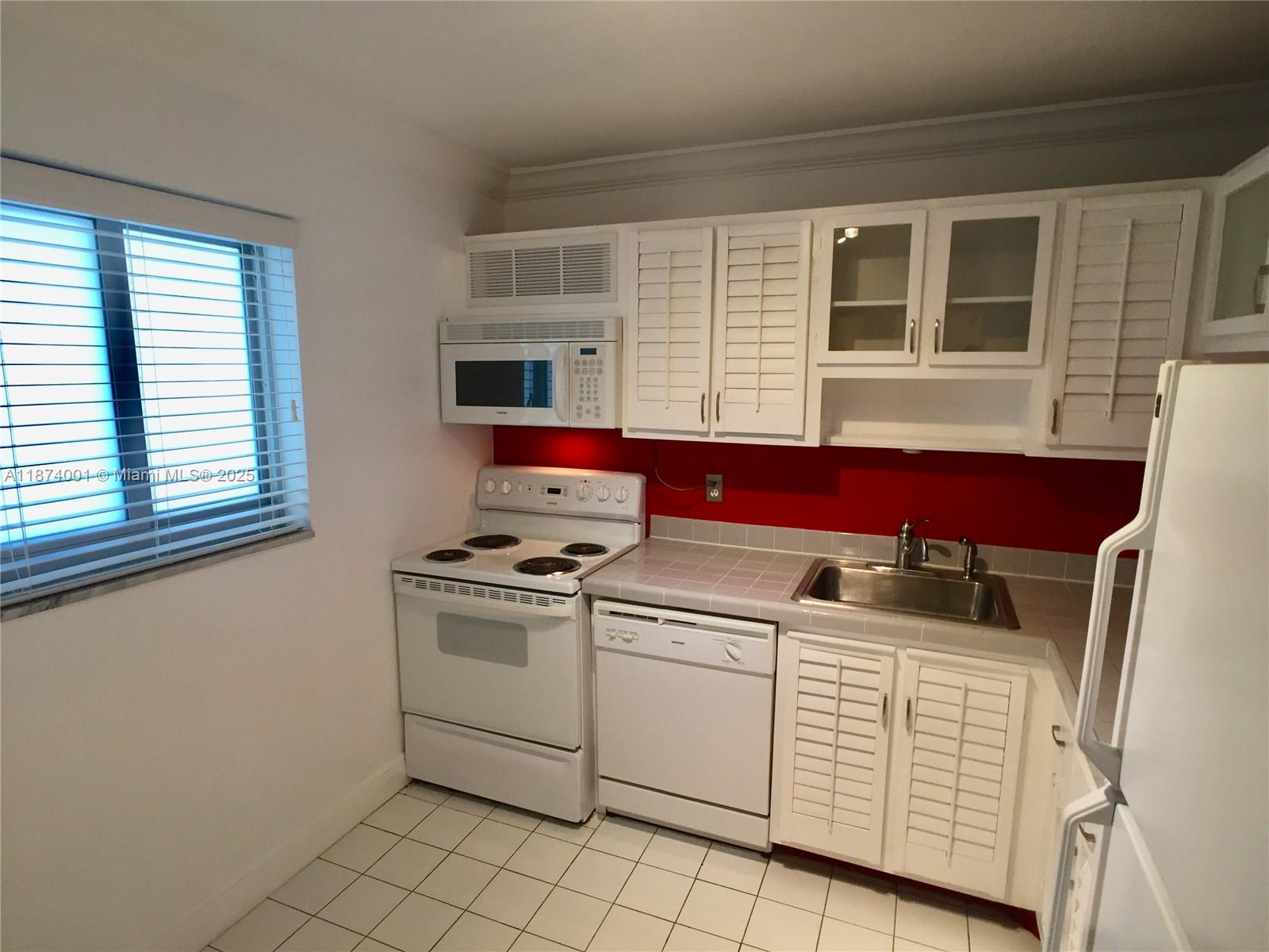 1025 Alton Road, Unit 507 Miami Beach, FL 33139 - Photo 25 of 28 a kitchen with white cabinets and white appliances