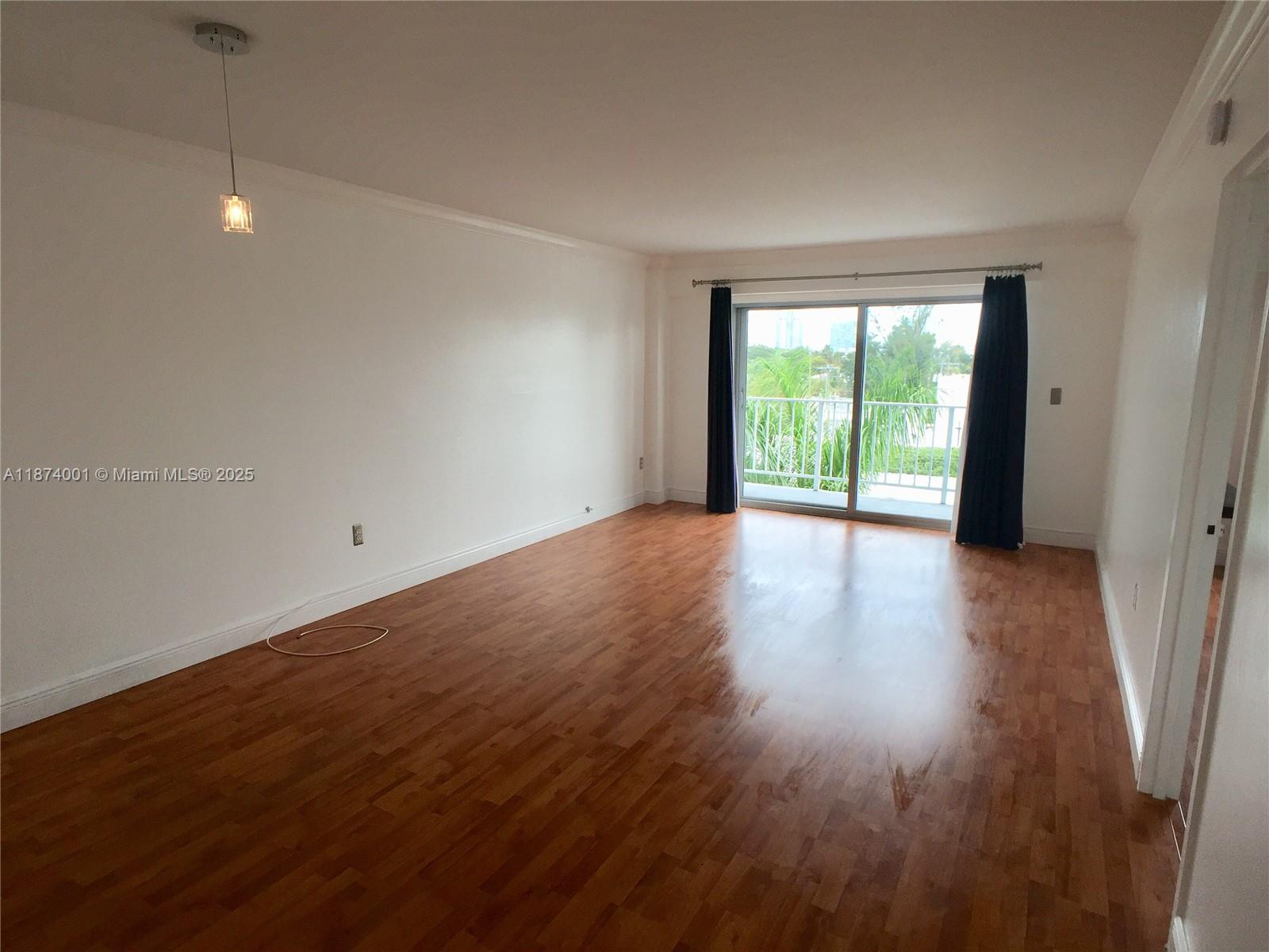 1025 Alton Road, Unit 507 Miami Beach, FL 33139 - Photo 3 of 28 an empty room with wooden floor and windows