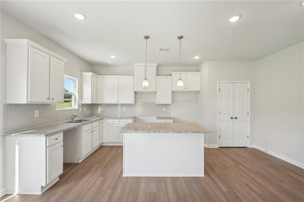 11124 Suria Drive Covington, GA 30014 - Photo 15 of 31 a large kitchen with cabinets wooden floor and stainless steel appliances