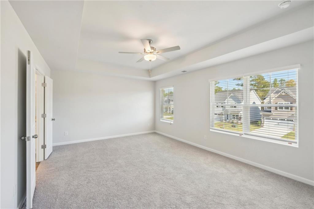 11124 Suria Drive Covington, GA 30014 - Photo 26 of 31 an empty room with chandelier fan and windows
