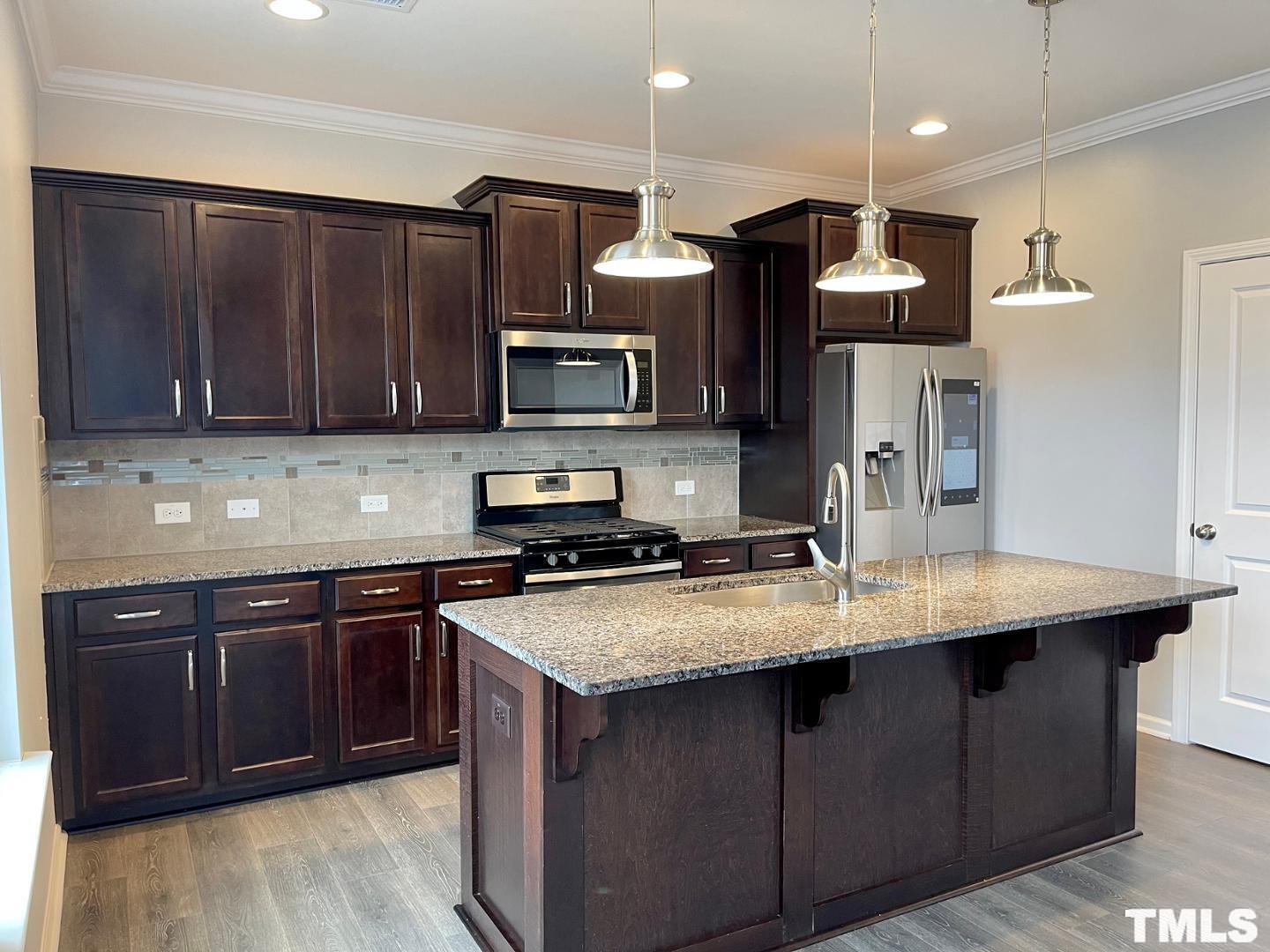 343 Great Northern Station Apex, NC 27502 - Photo 12 of 29 a kitchen with stainless steel appliances wooden cabinets a stove a sink and a refrigerator