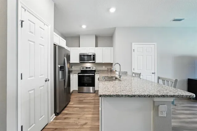 a kitchen with stainless steel appliances granite countertop a refrigerator a stove and a sink