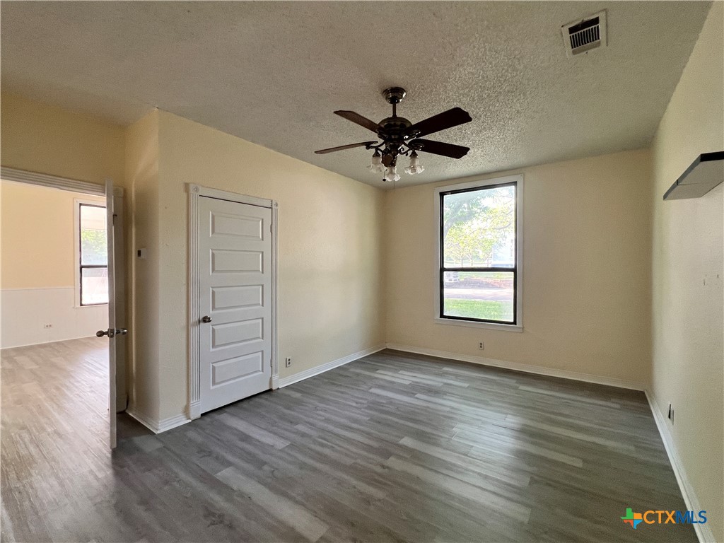 902 North 1st Street Temple, TX 76501 - Photo 11 of 29 an empty room with wooden floor chandelier fan and windows