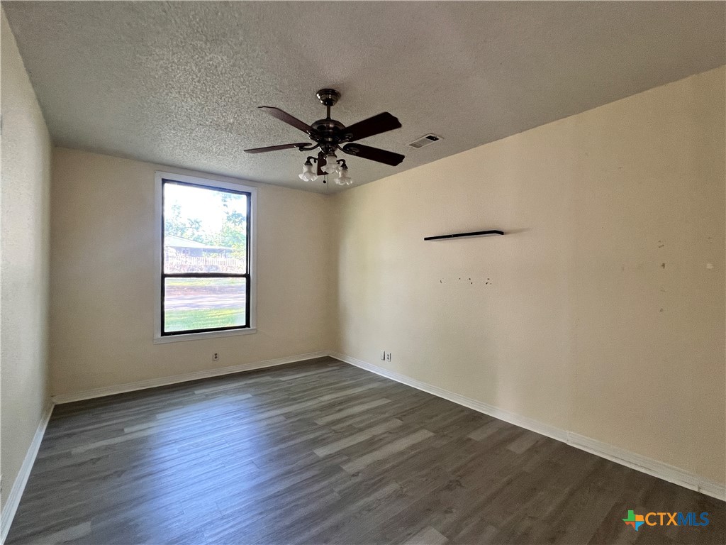 902 North 1st Street Temple, TX 76501 - Photo 10 of 29 an empty room with wooden floor fan and windows