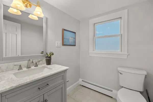 a bathroom with a granite countertop sink mirror vanity and toilet