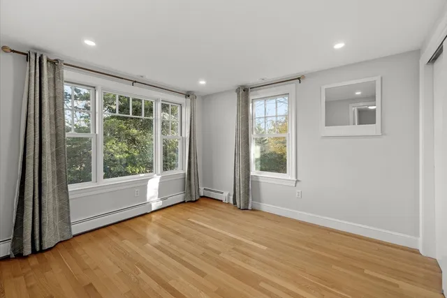 a view of an empty room with a window and wooden floor