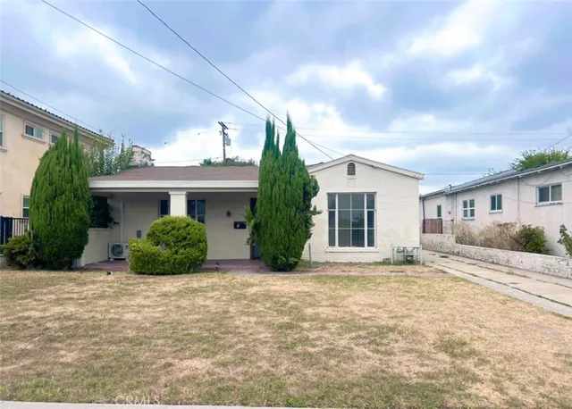 a view of a house with a yard and potted plants