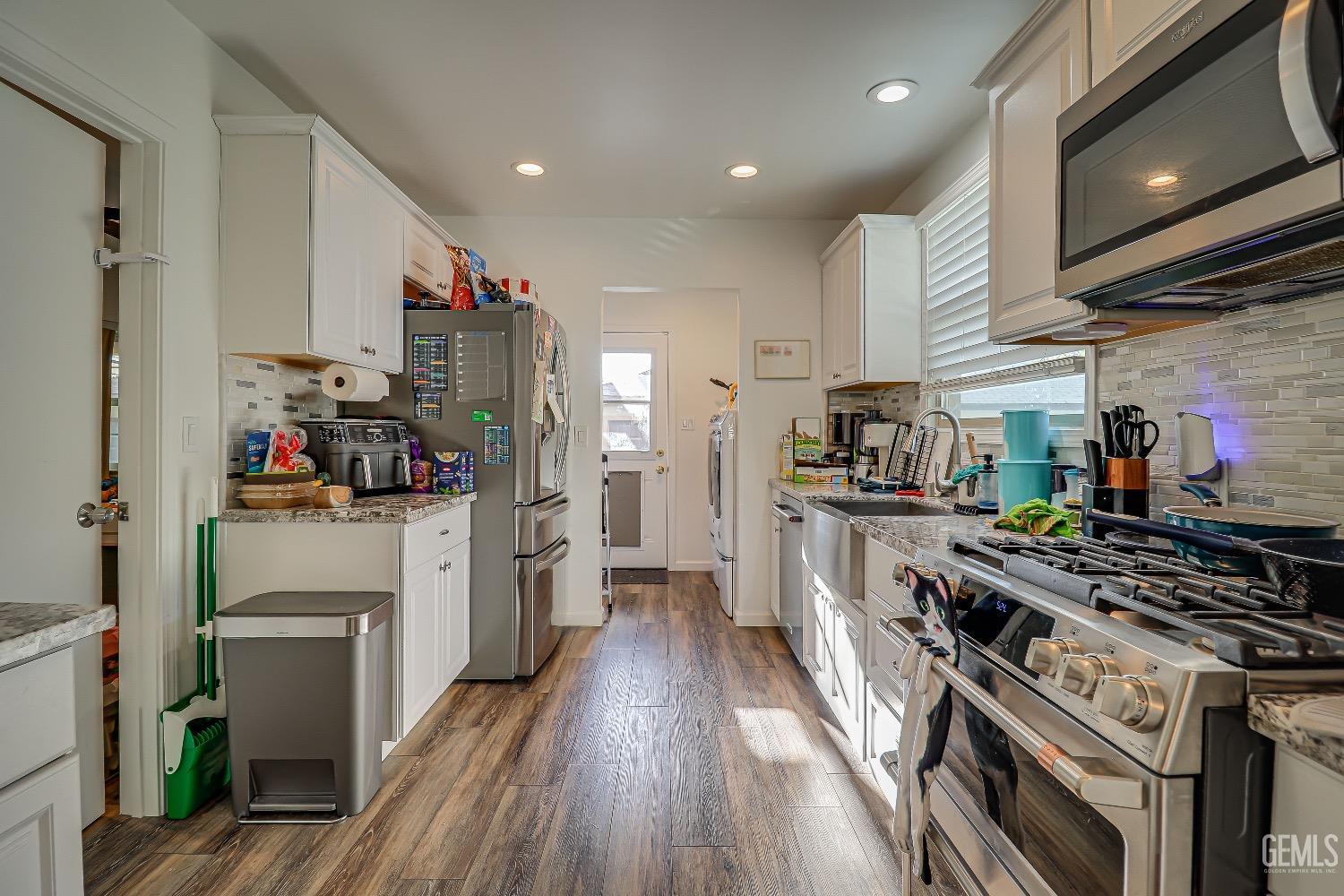 Undisclosed Address Bakersfield, CA 93304 - Photo 9 of 26 a kitchen with refrigerator a stove and wooden floor