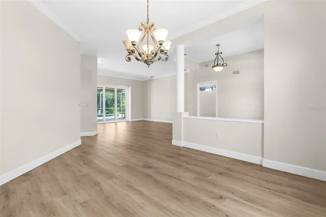 an empty room with wooden floor chandelier fan and windows